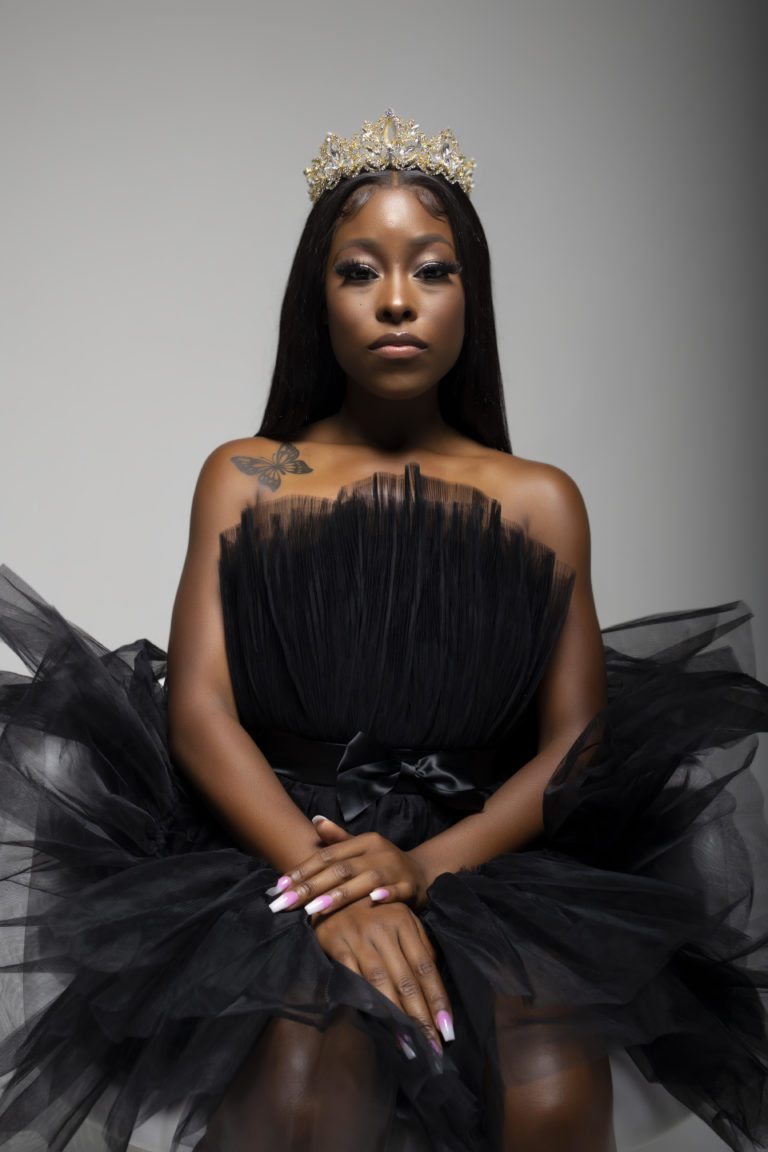 Woman in black dress wearing a tiara in a photography studio