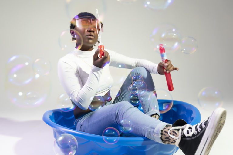 Woman sitting in a kiddie pool blowing bubbles