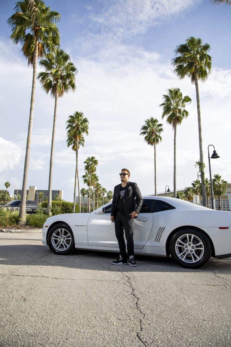 Man standing beside a Camera near palm trees